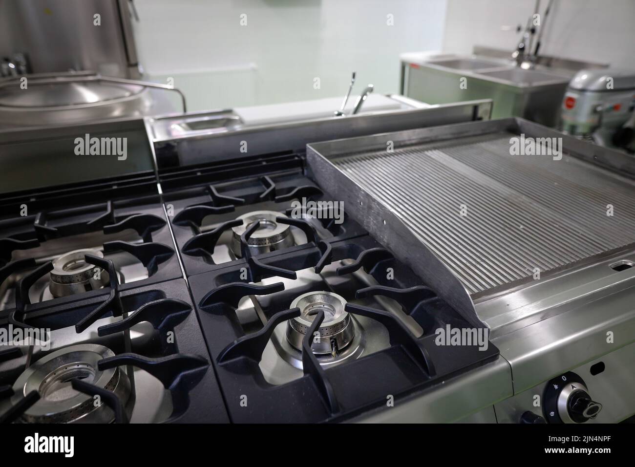 Shallow depth of field (selective focus) details with a brand new, unused, professional metallic gas burner in a restaurant kitchen. Stock Photo