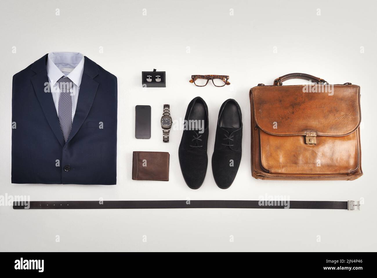Flatlay of business suit, corporate formal attire with fashion accessories  on a white table background. Still life above view of modern clothing style  with phone for a professional and neat lifestyle Stock