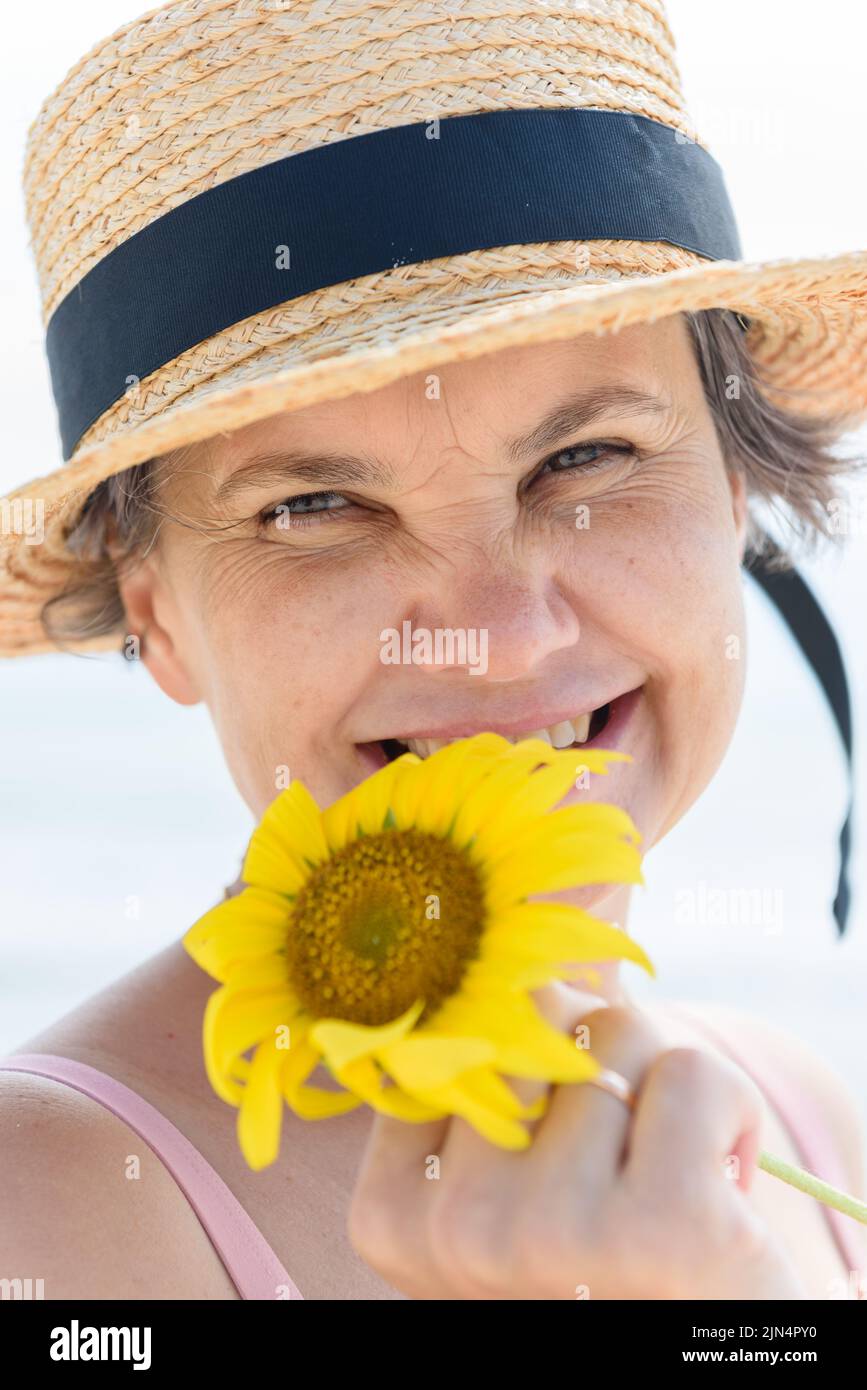 Married woman in a straw hat with a sunflower in her hand laughing at ...