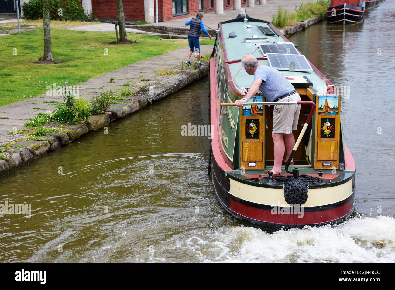 Chester, UK: Jul 3, 2022: A couple carefully manoeuvre their narrowboat in the Chester Canal Basin of the Shropshire Union Canal Stock Photo