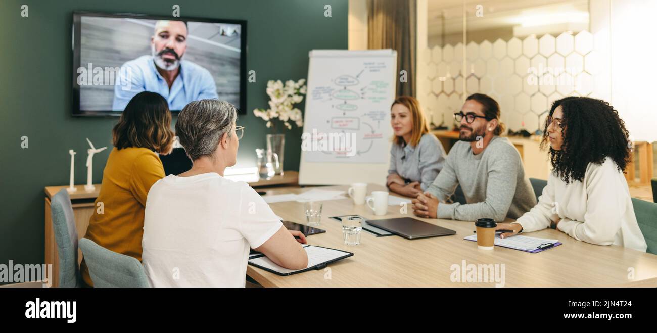 Multicultural businesspeople having a video conference in a boardroom. Group of innovative business professionals sharing creative ideas while working Stock Photo