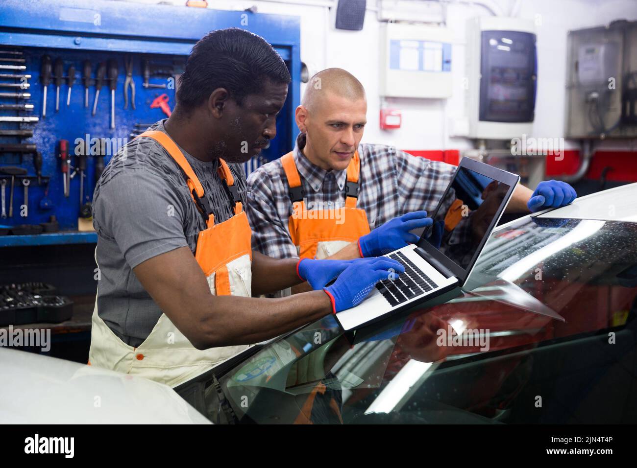 Mechanic and assistant working at service Stock Photo - Alamy
