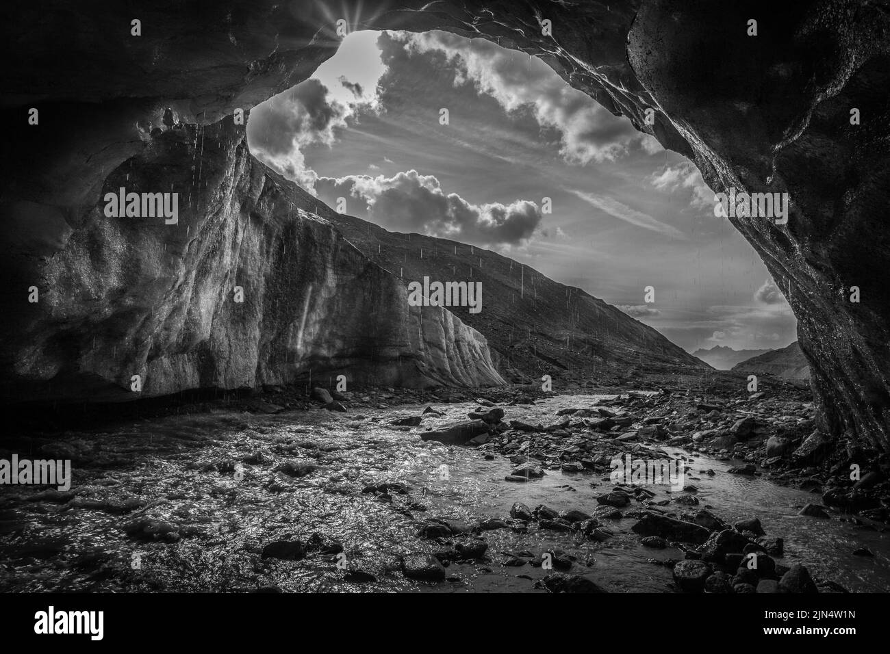 Black and white effect of glacial stream that coming out of a cave into ice Stock Photo