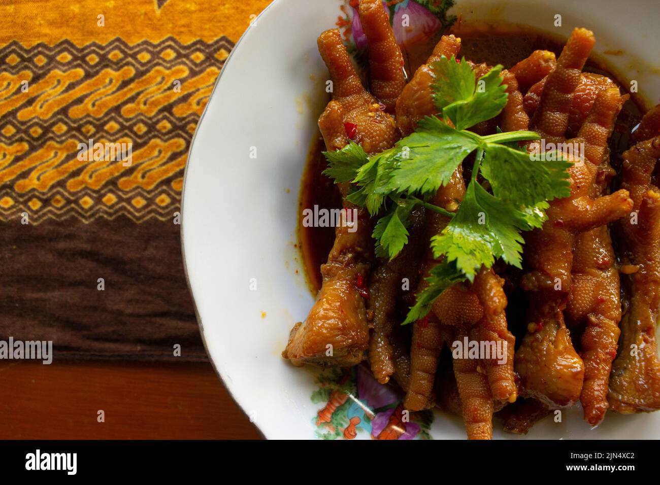 Spicy chicken feet with celery, chili, onion, garlic served with a white plate on table Stock Photo