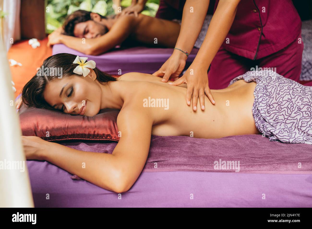 Shot of couple lying on front at spa center and having back massage. Focus to woman. Stock Photo