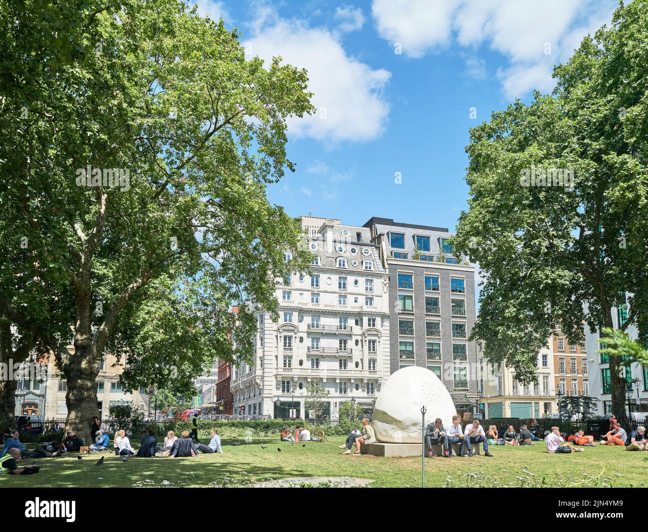 Office workers relax, during their lunch break, at Hanover Square gardens, Mayfair, London, England, on a sunny summer day. Stock Photo