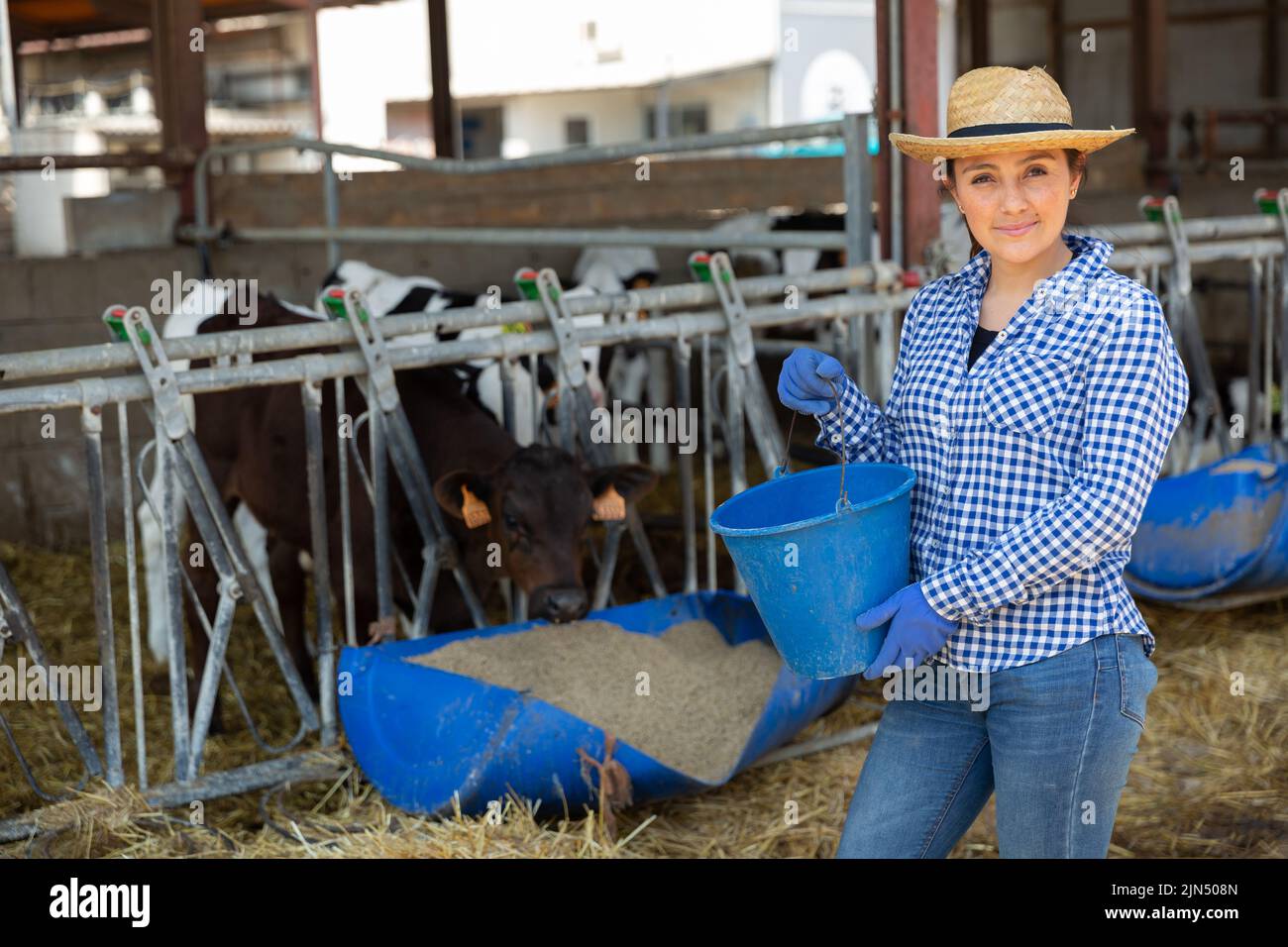 Portrait of a positive woman farmer standing in a cowshed, holding a ...