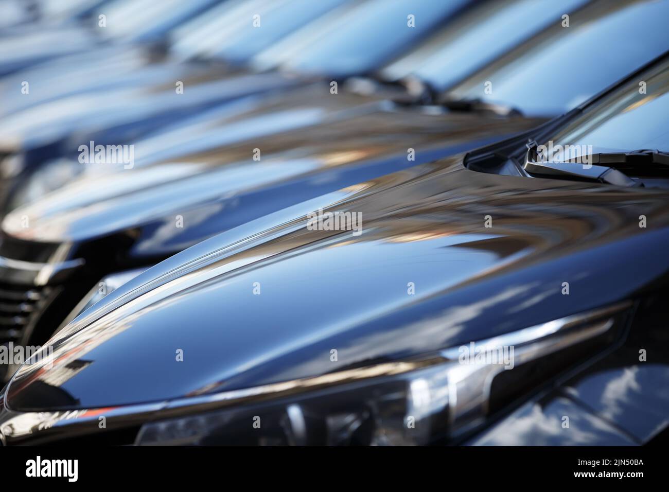 The hood of the car. Row of cars on a parking lot. Black sedan cars standing in a row.  Fleet of generic modern cars. Transportation. Many similar new Stock Photo
