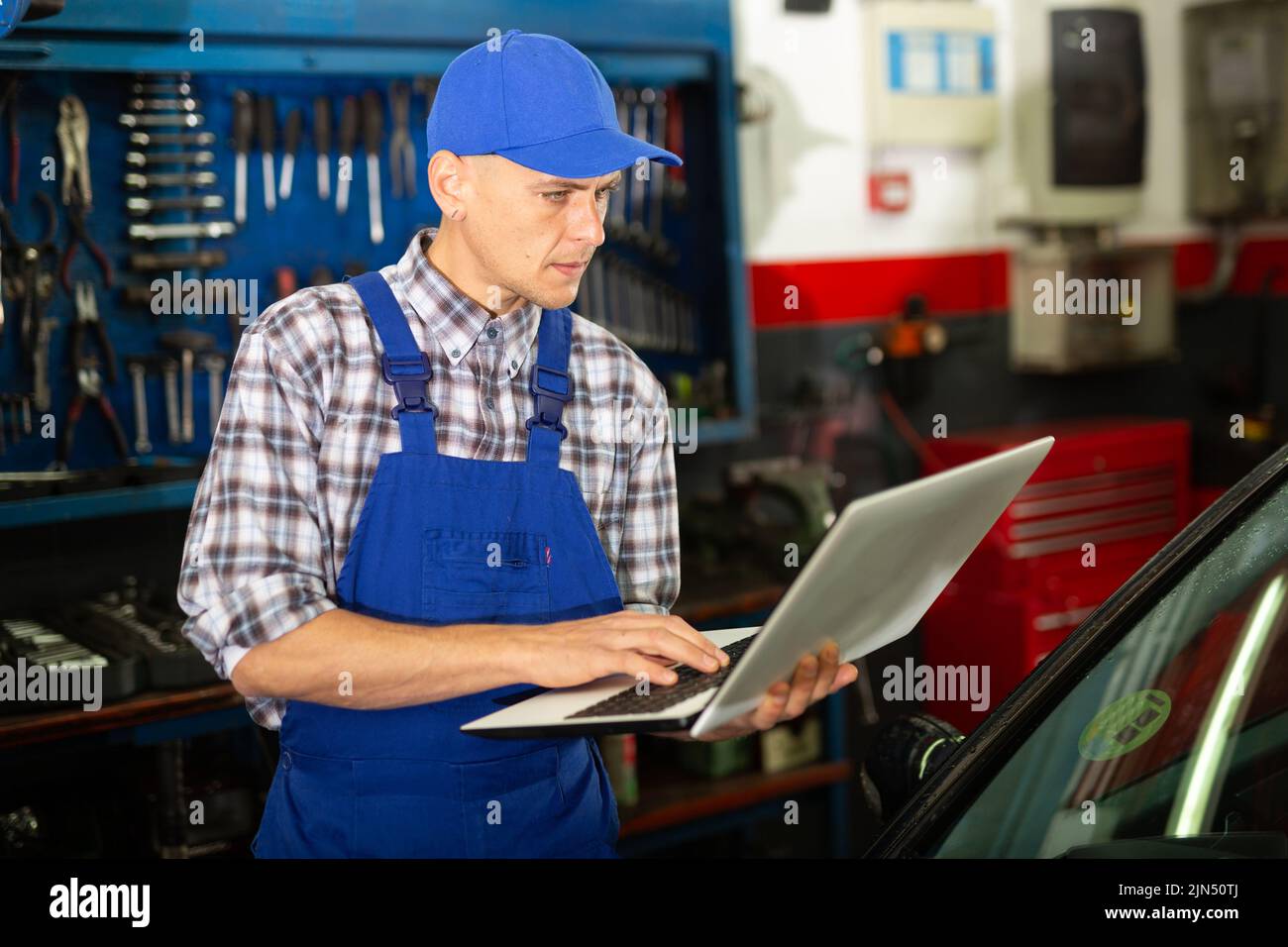 Mechanic with laptop near car engine in auto service Stock Photo Alamy