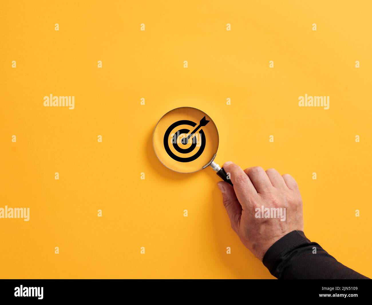 Hand holding a magnifier over the target icon. Focusing on a target