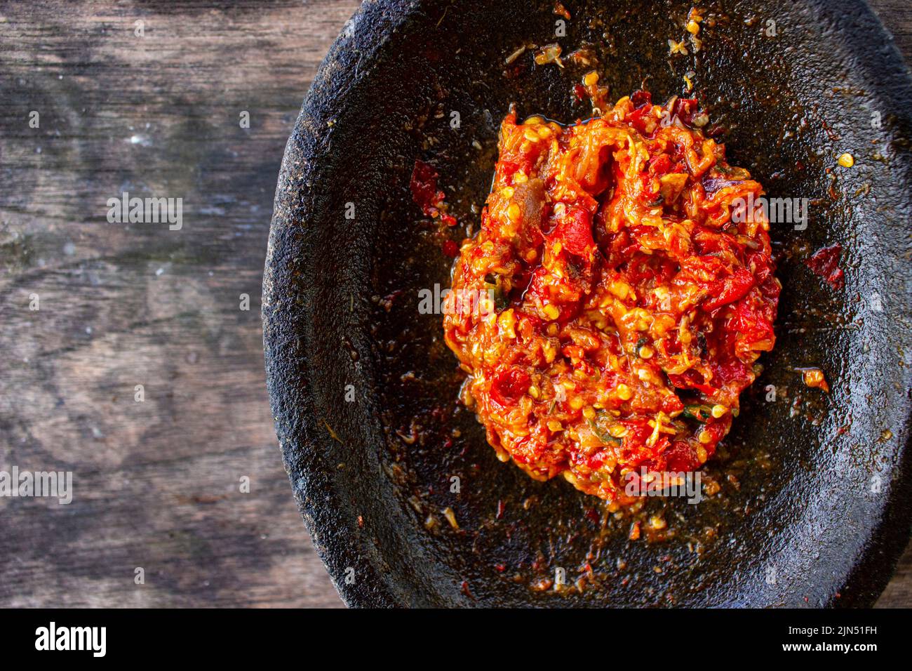 fresh sambal served on stone mortar (cobek). sambal is traditional sauce from indonesia made from chili Stock Photo