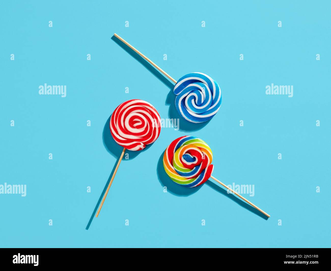Colorful swirl round candy lollipops on blue background. Stock Photo