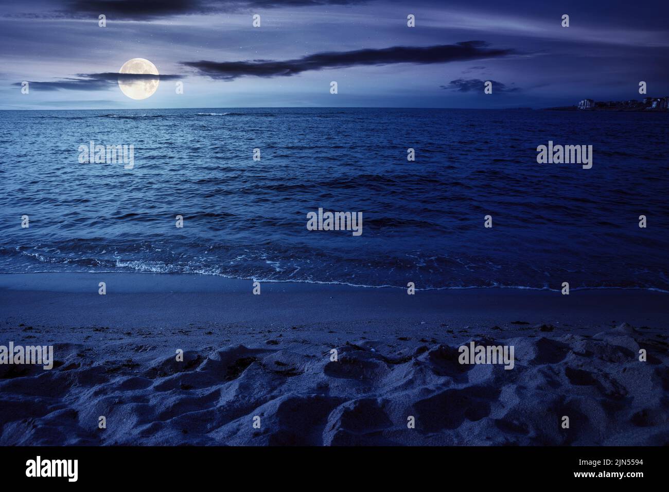 night scenery at the sea. calm waves washing the sandy beach in full moon light. transparent water and bright blue sky Stock Photo