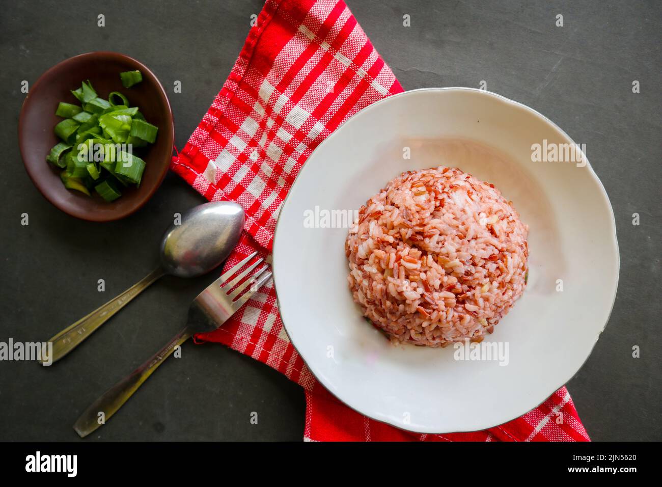 Red steamed rice or nasi merah served in plate isolated on black ...