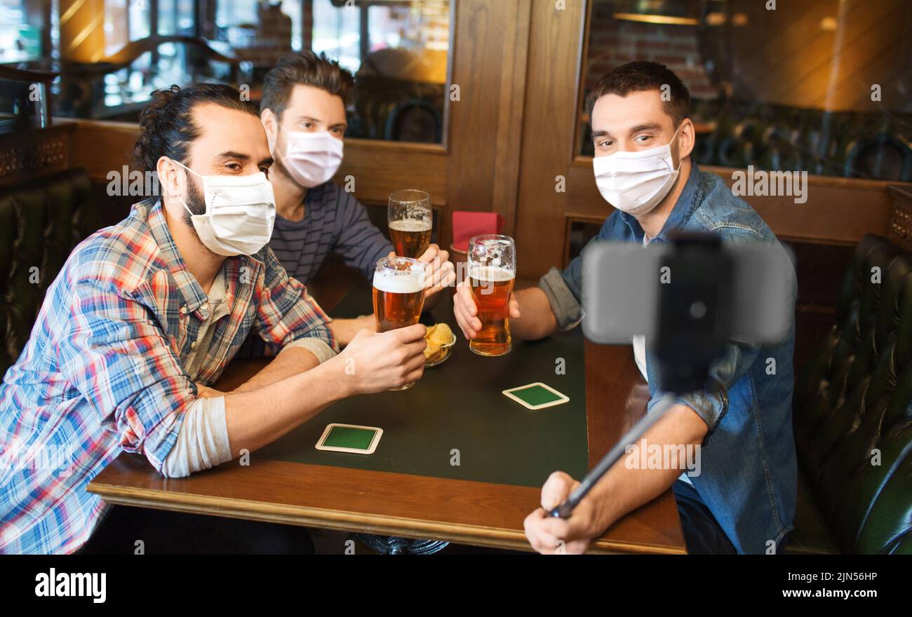men in masks take selfie and drink beer at bar Stock Photo