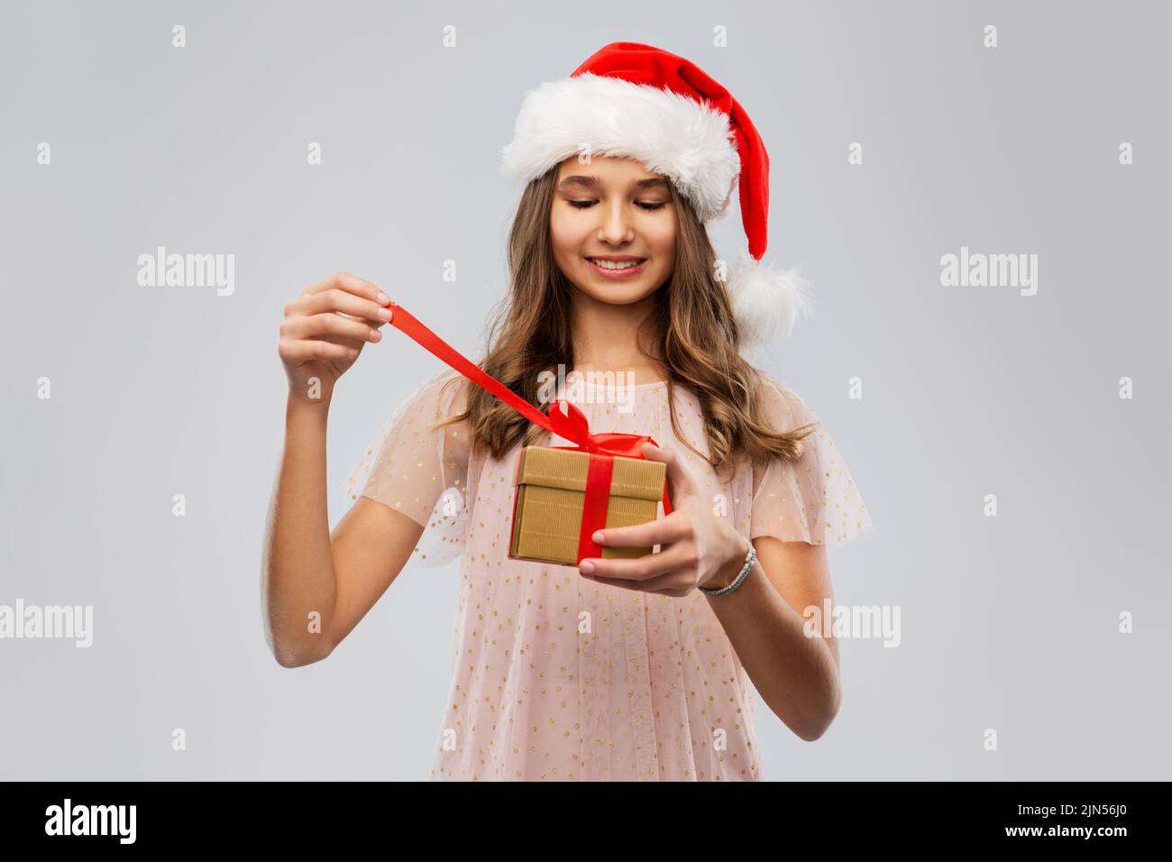 teenage girl in santa hat opening christmas gift Stock Photo