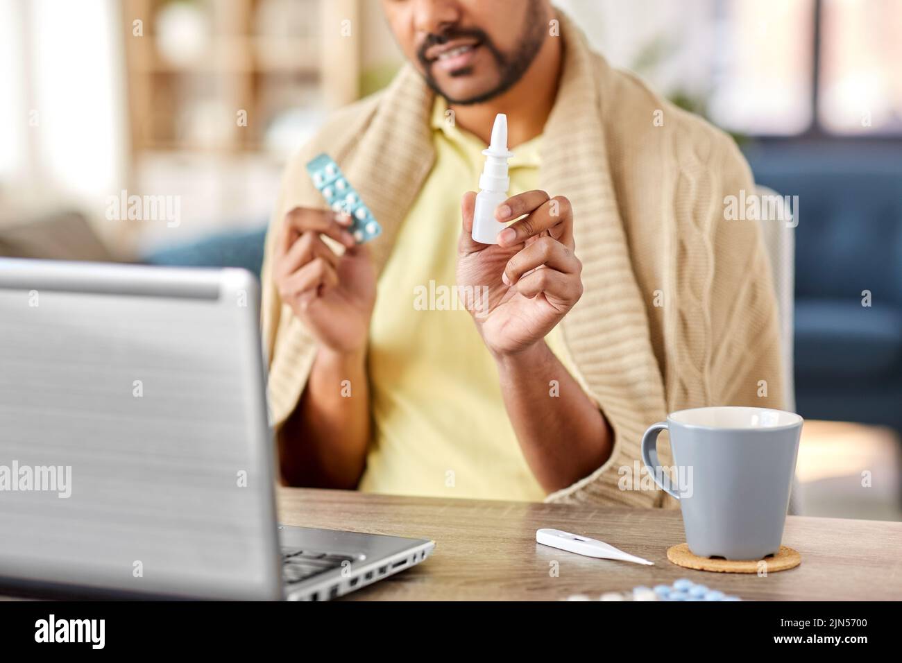 sick man thermometer having video call on laptop Stock Photo