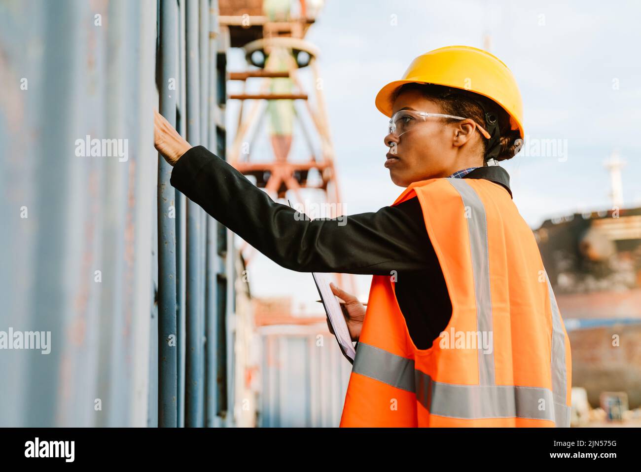 Black woman wearing helmet and vest working in port outdoors Stock ...