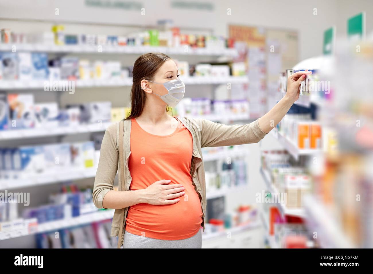 pregnant woman in mask buys medicine at pharmacy Stock Photo