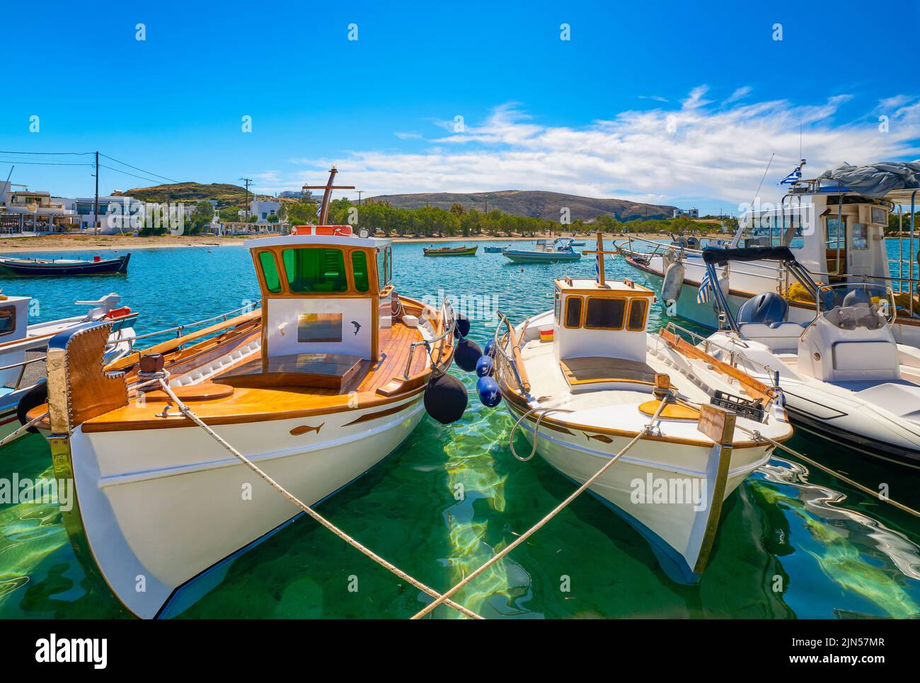 Beautiful view of Greek fishing boats anchored in a small village. Whitewashed houses, fishing boat, clear blue sky, bay, sea, hills. Milos, Greece Stock Photo