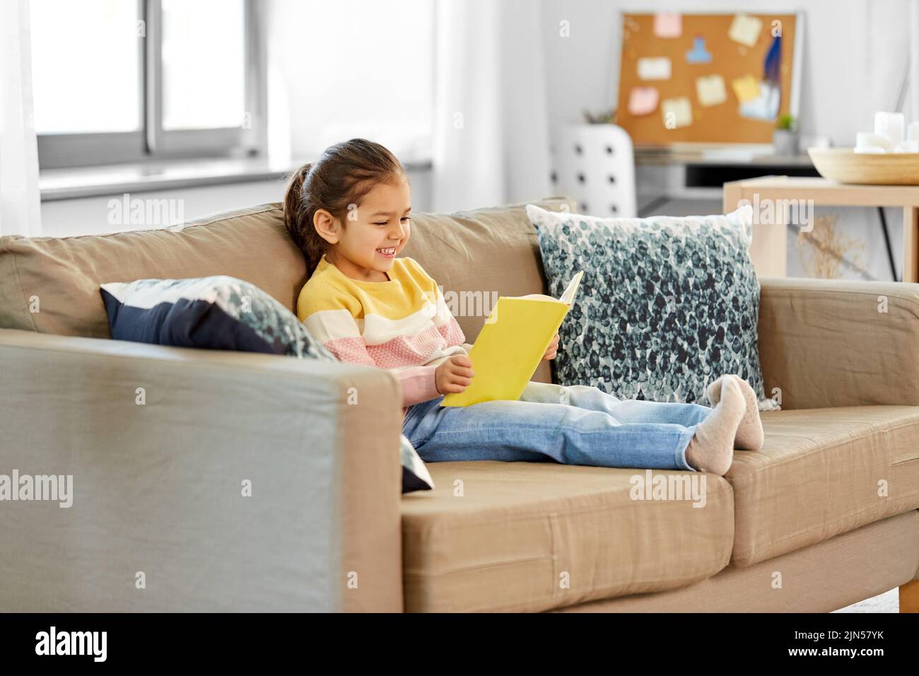 happy smiling little girl reading book at home Stock Photo - Alamy