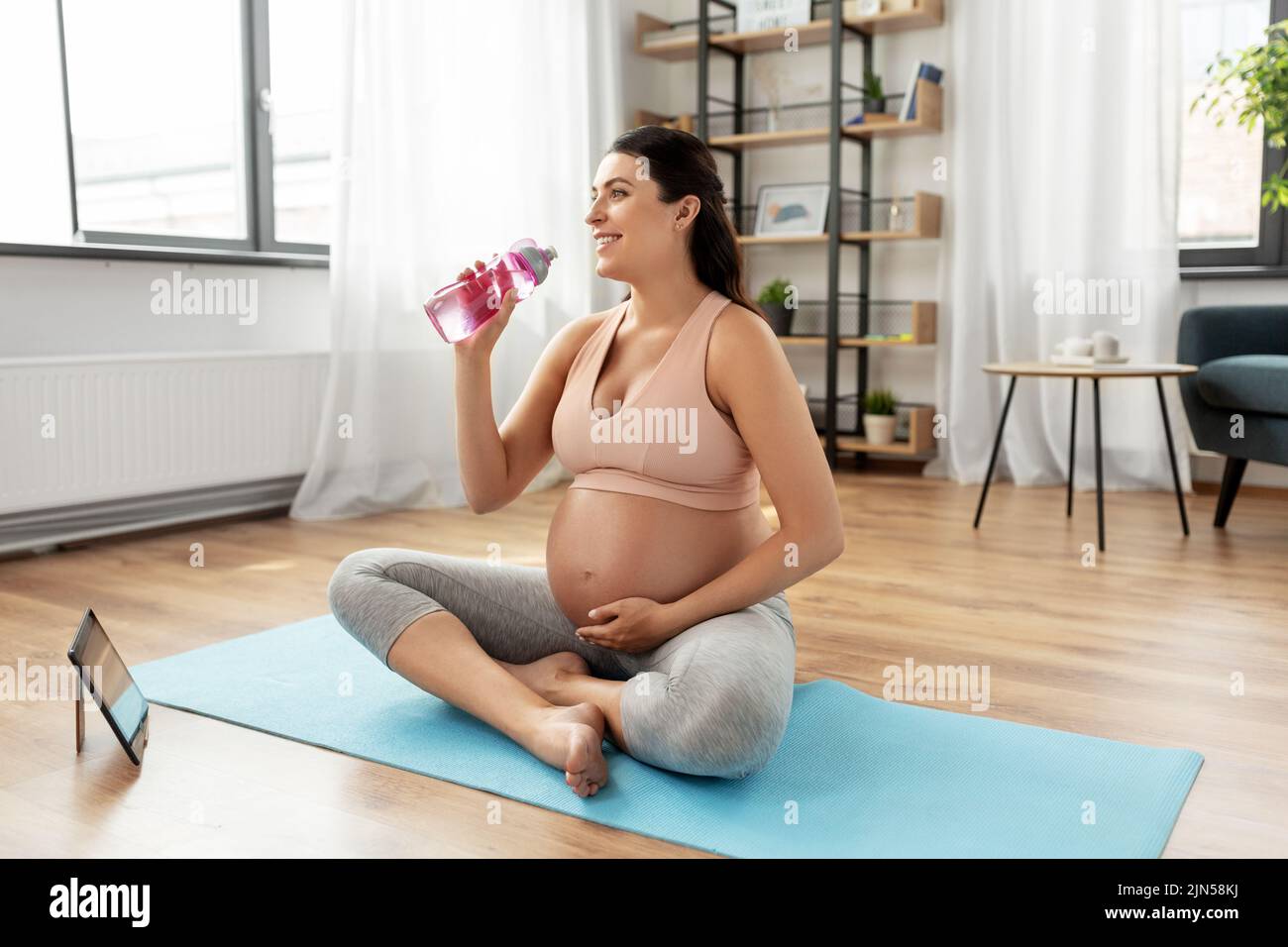 pregnant woman drinking water after yoga at home Stock Photo