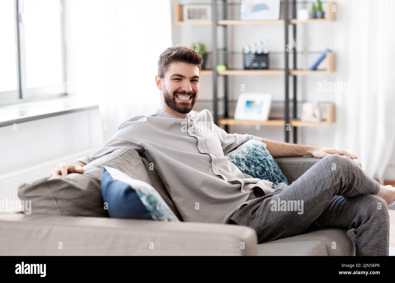happy smiling man sitting on sofa at home Stock Photo