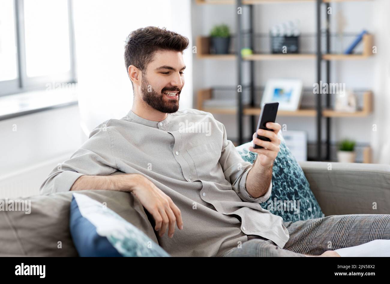 happy smiling young man with smartphone at home Stock Photo