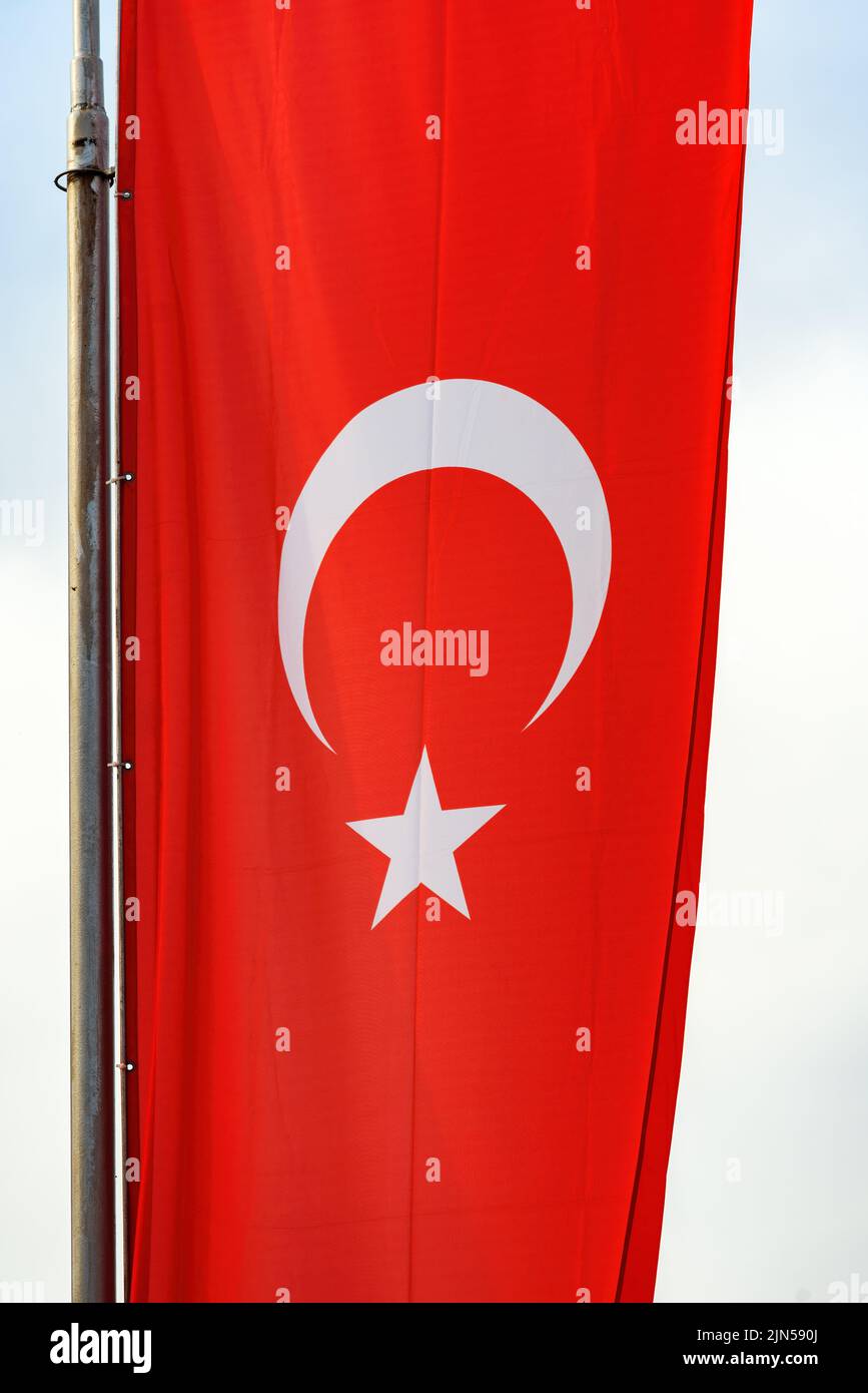 National flag of Turkey or Republic of Turkiye on post. Red banner with white star and crescent. Vertical image. Stock Photo