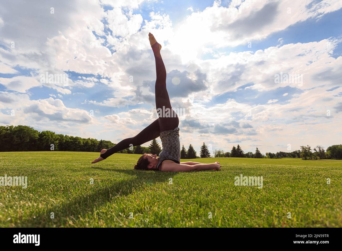 Young healthy woman doing yoga in the sunny summer park. Fitness and healthy lifestyle Stock Photo