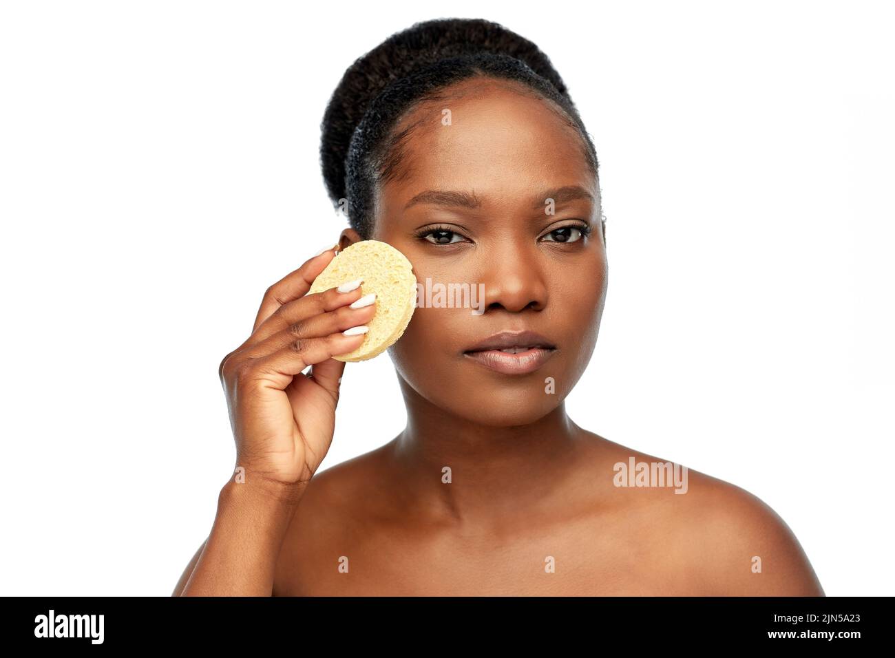 young woman cleaning face with exfoliating sponge Stock Photo