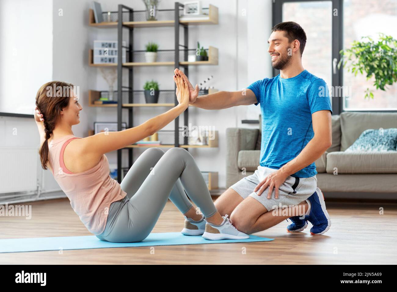 woman with personal trainer doing sit ups at home Stock Photo