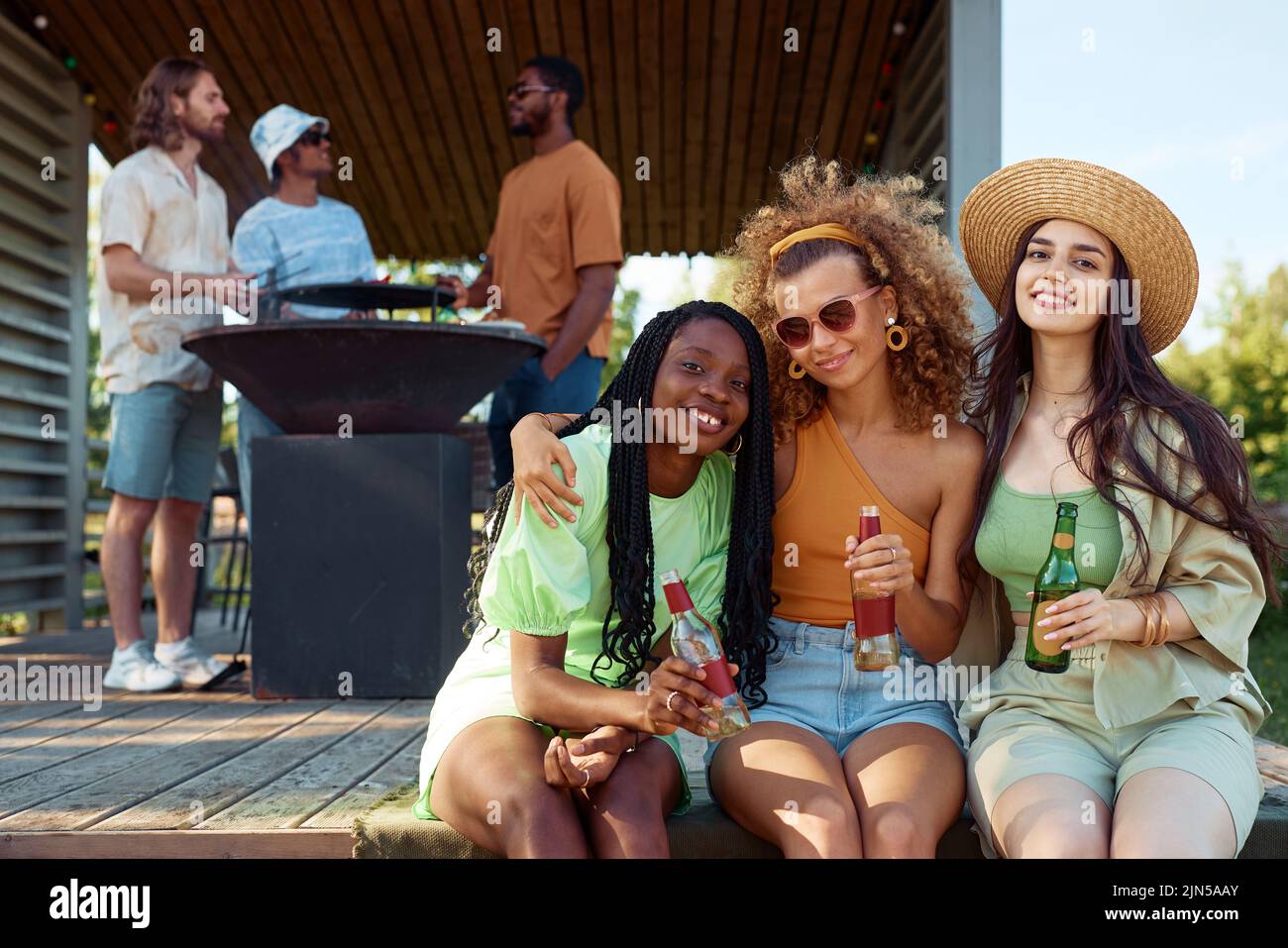 Diverse group of girls looking at camera while enjoying party outdoors with friends in Summer cabin, copy space Stock Photo