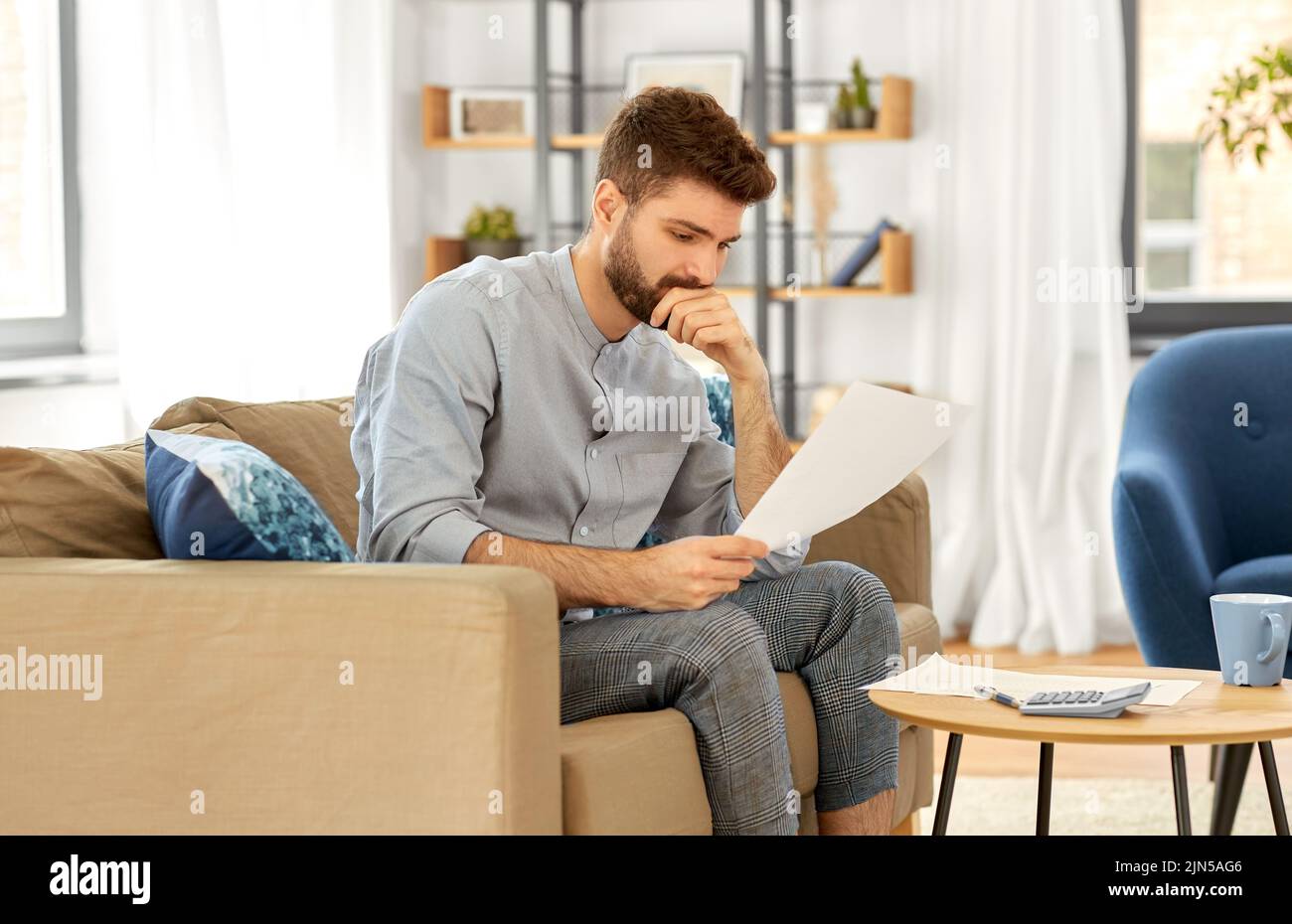 man with bills counting on calculator at home Stock Photo Alamy