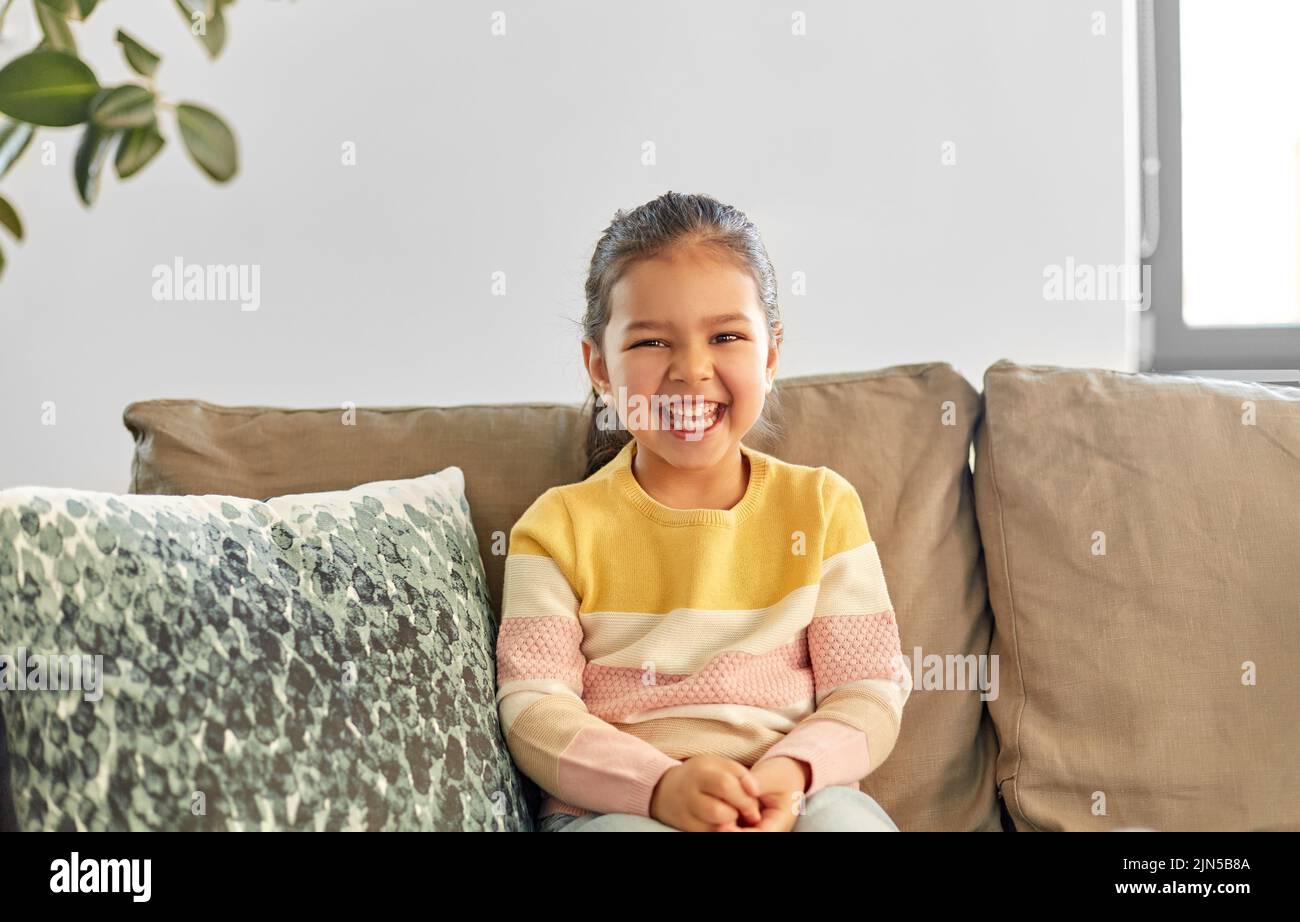 happy smiling little girl sitting on sofa at home Stock Photo - Alamy