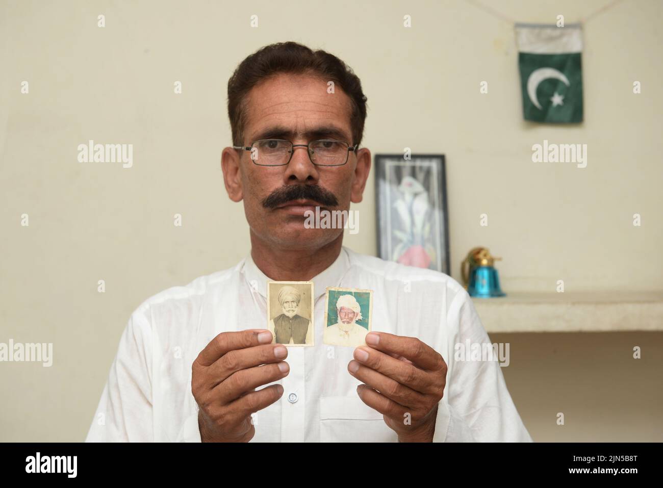 05 August 2022, Pakistan, Faisalabad: Shahbaz Khan shows pictures of his uncle Inayat Khan (left), who was also separated from the family at the time of partition and died in India a few years ago, and his late father Sharif Khan. They are the brothers of Pritam Khan. When the British announced the partition of their former colonial empire British India into India and Pakistan in 1947, his uncle was about nine years old. In the sectarian riots that followed the partition, Pritam lost his family, who fled to Pakistan. Today he is back in contact with his nephew Shahbaz. Photo: Murtaza Ali/dpa Stock Photo