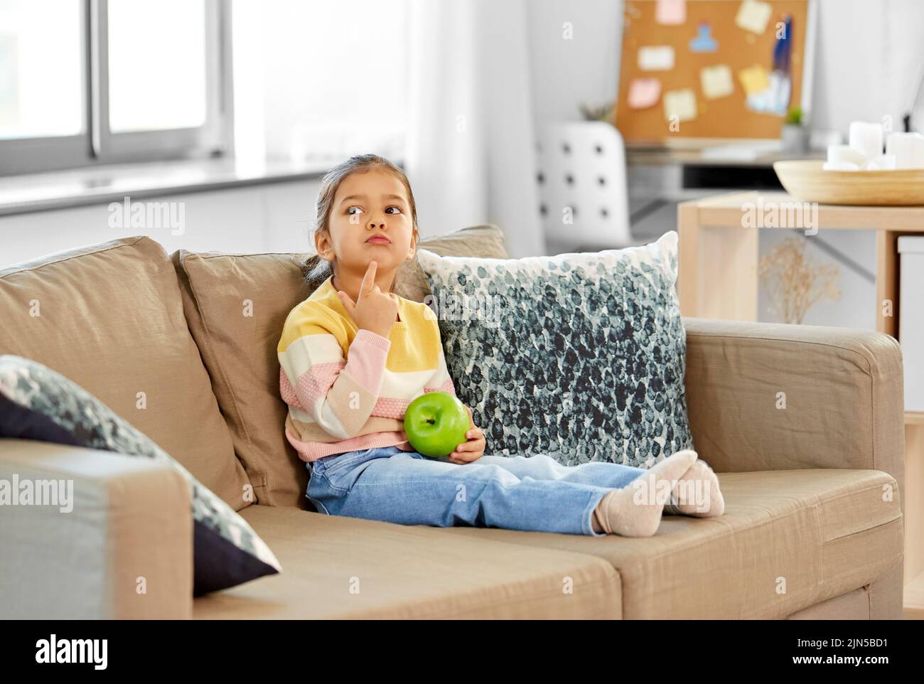 little girl with apple sitting on sofa Stock Photo - Alamy
