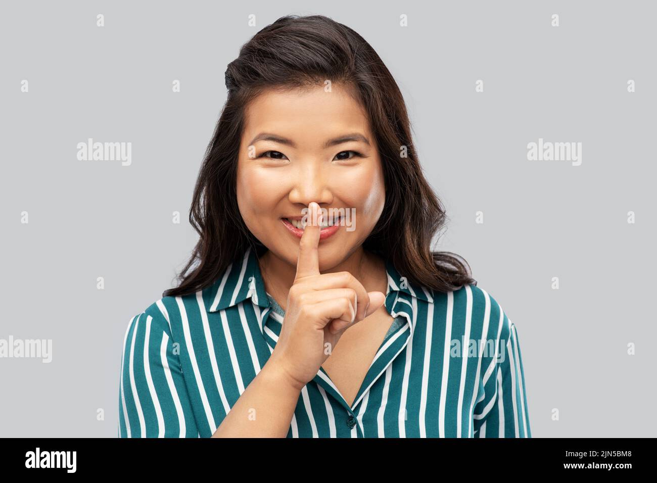 portrait of happy asian woman making hush gesture Stock Photo