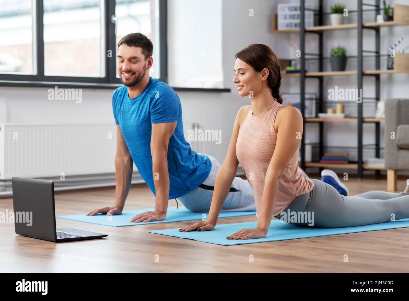 happy couple with laptop exercising at home Stock Photo