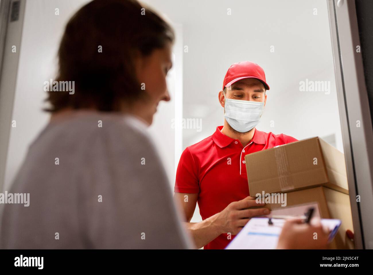 delivery man in mask with parcel and customer Stock Photo