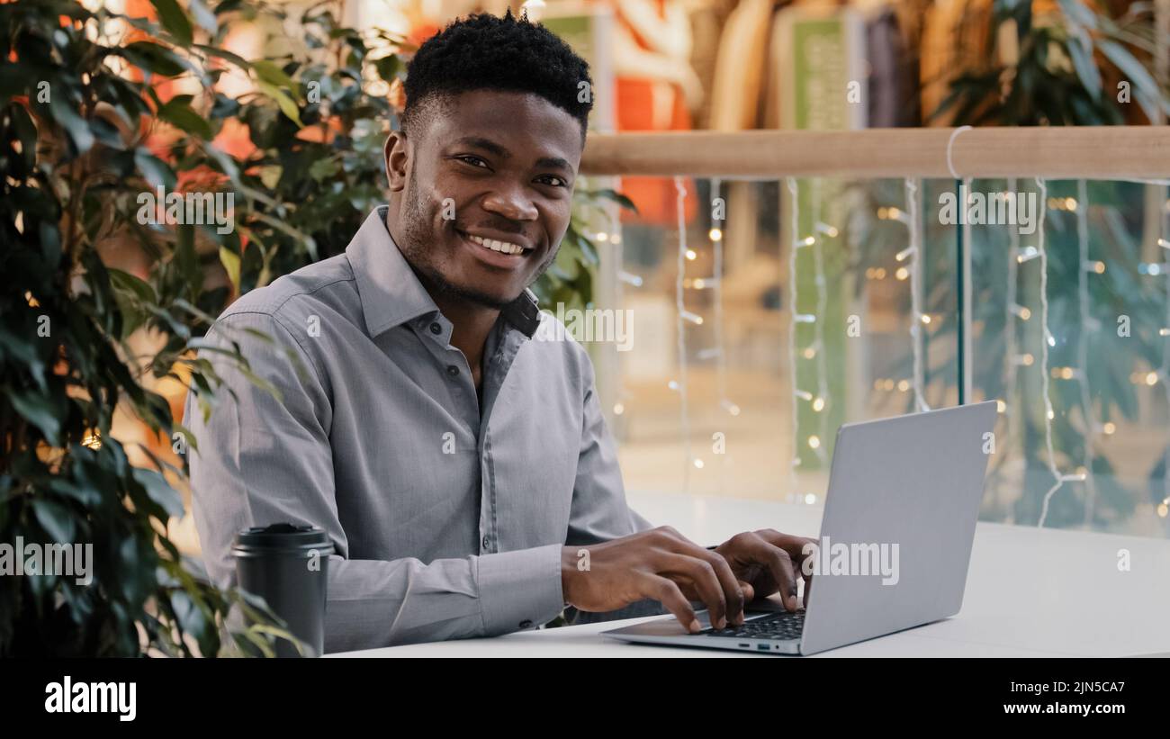 Focused young male freelancer working online typing on laptop happy guy student successful businessman turning looking at camera smiling using Stock Photo
