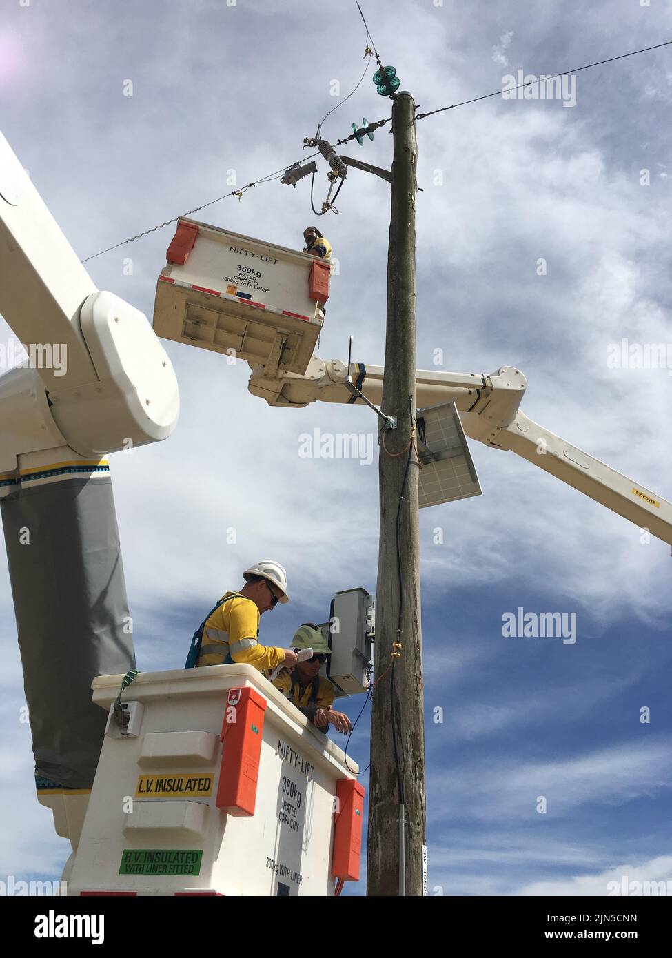 Powerline workers working on a pole Stock Photo
