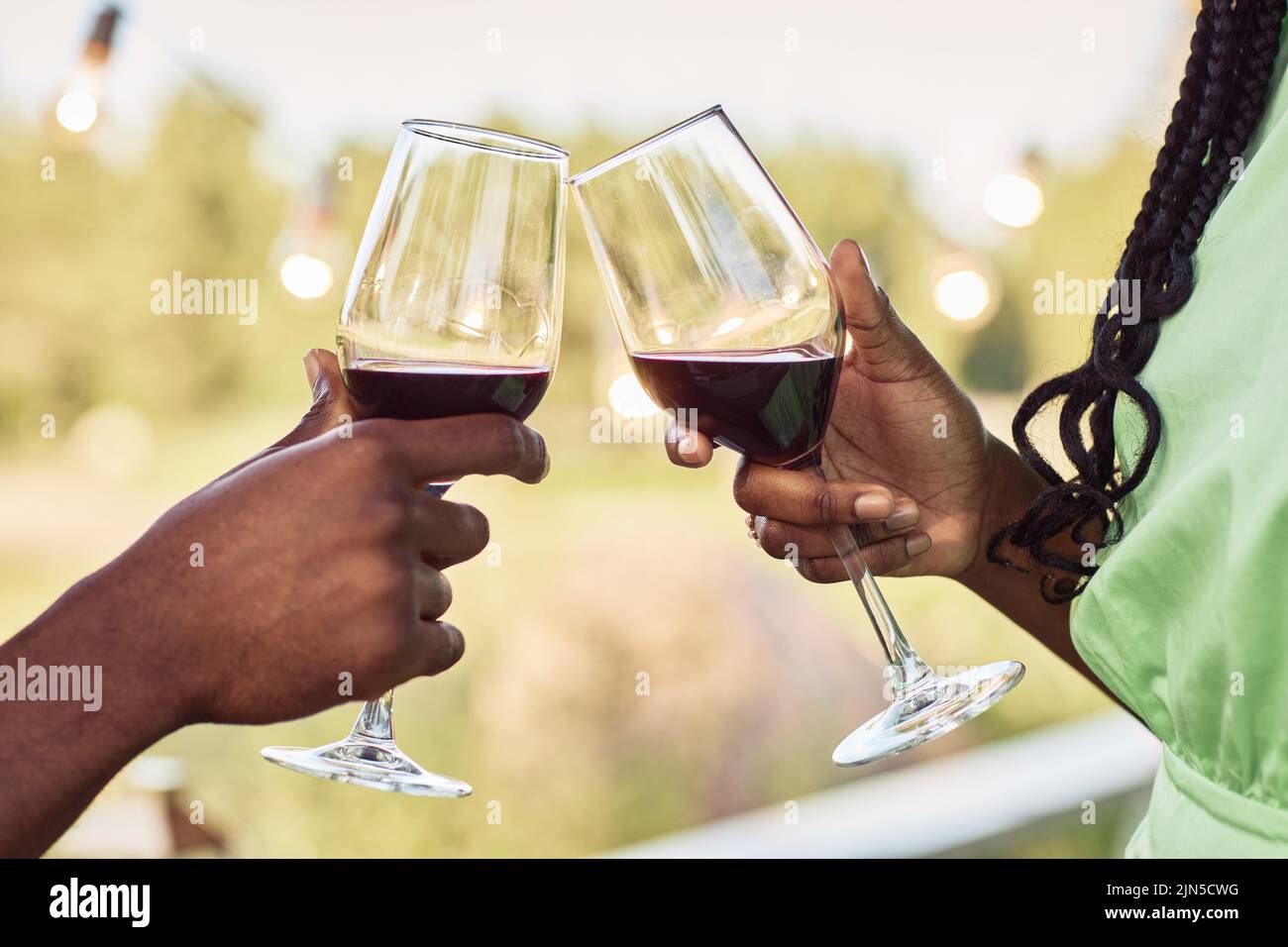 Close up of black young couple toasting and enjoying glass of wine at terrace during romantic date outdoors in Summer Stock Photo