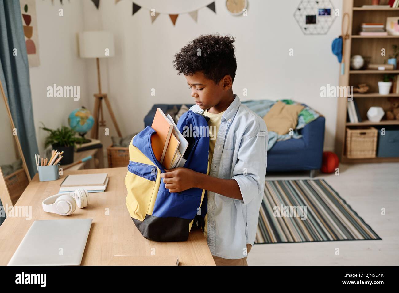Child preparing his school bag for school packing books and copybooks in it Stock Photo