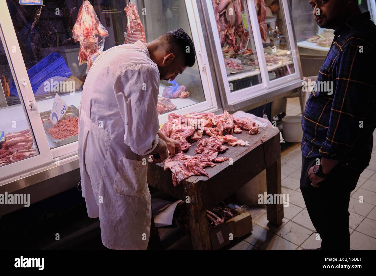 Butcher prepping chicken pieces fro customer inside the Central Municipal Market in Athens Stock Photo