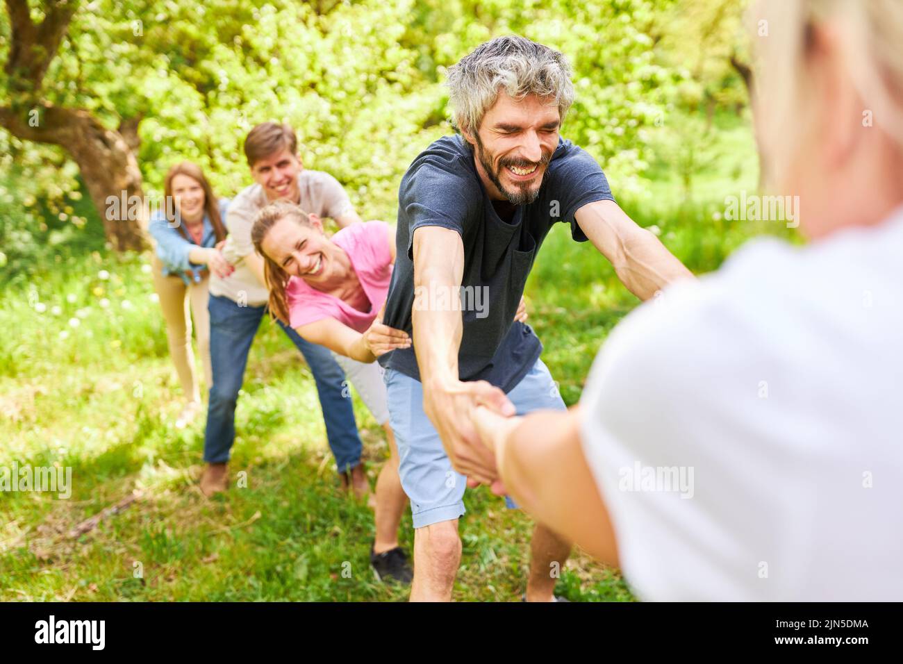 Young people pull hands during a showdown at the outdoor team event Stock Photo