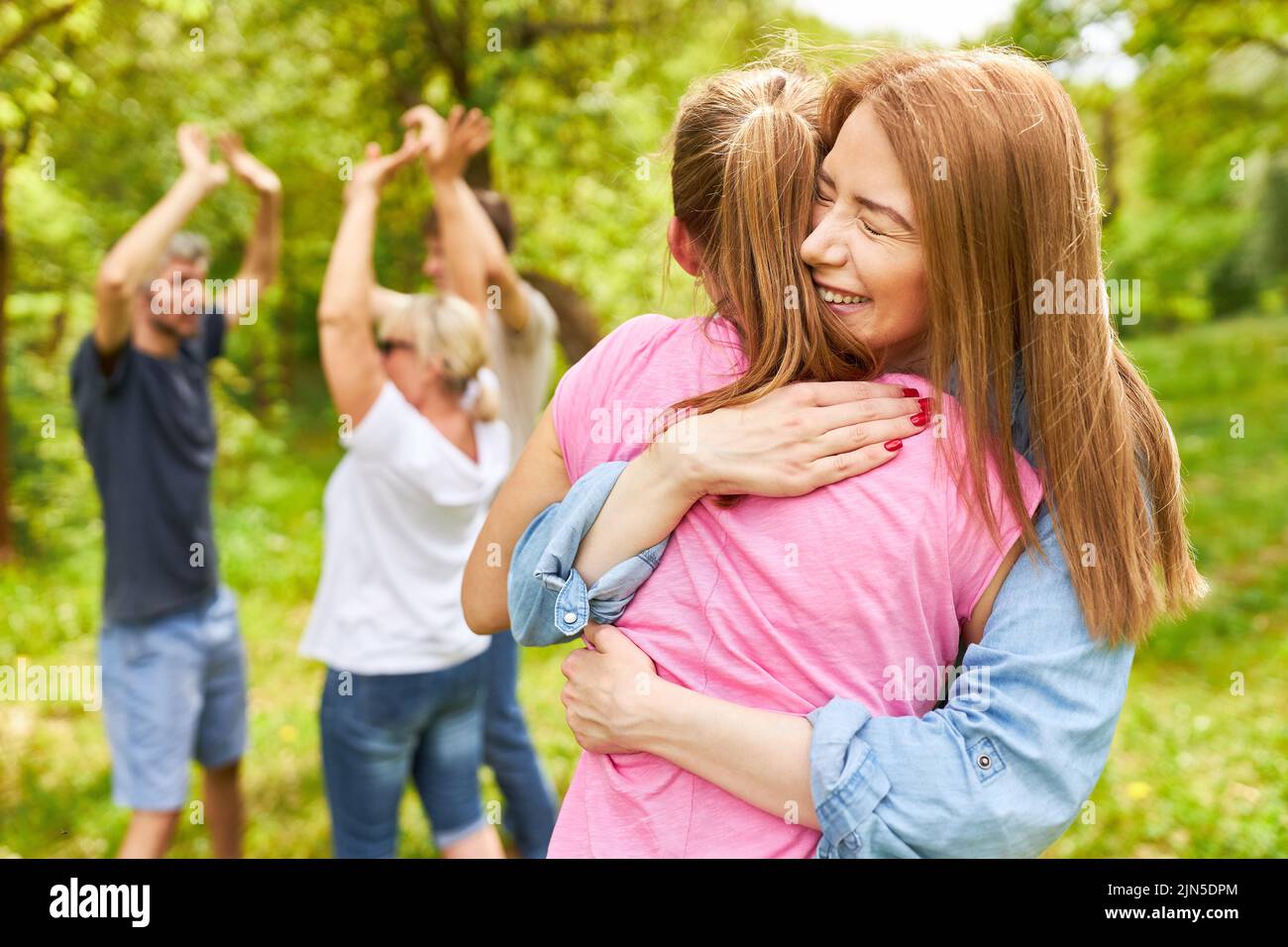 Two girlfriends happily hugging and celebrating a victory with their team Stock Photo