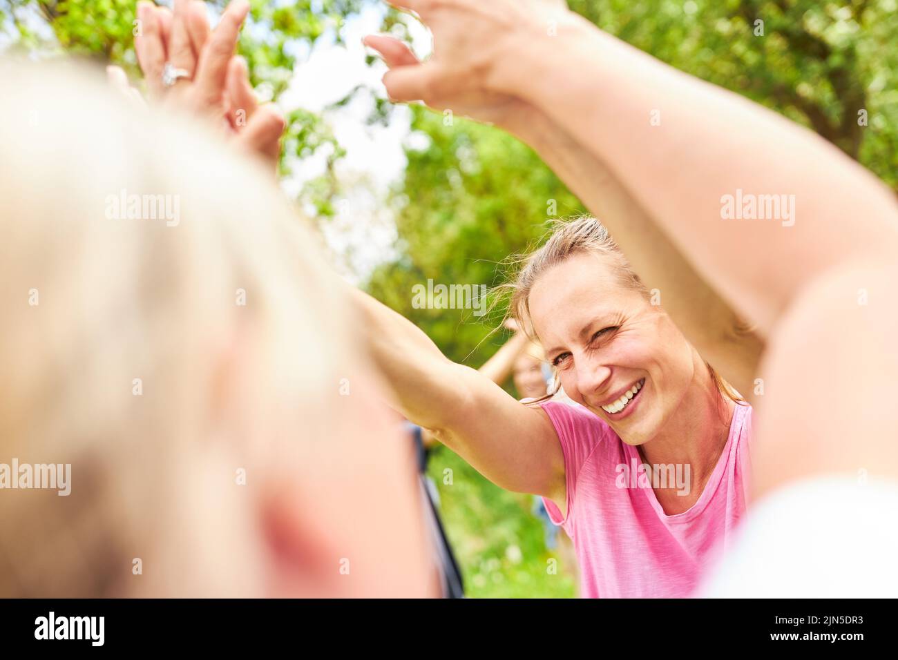 Young woman is happy with her team about a victory and celebrates success by giving high five Stock Photo