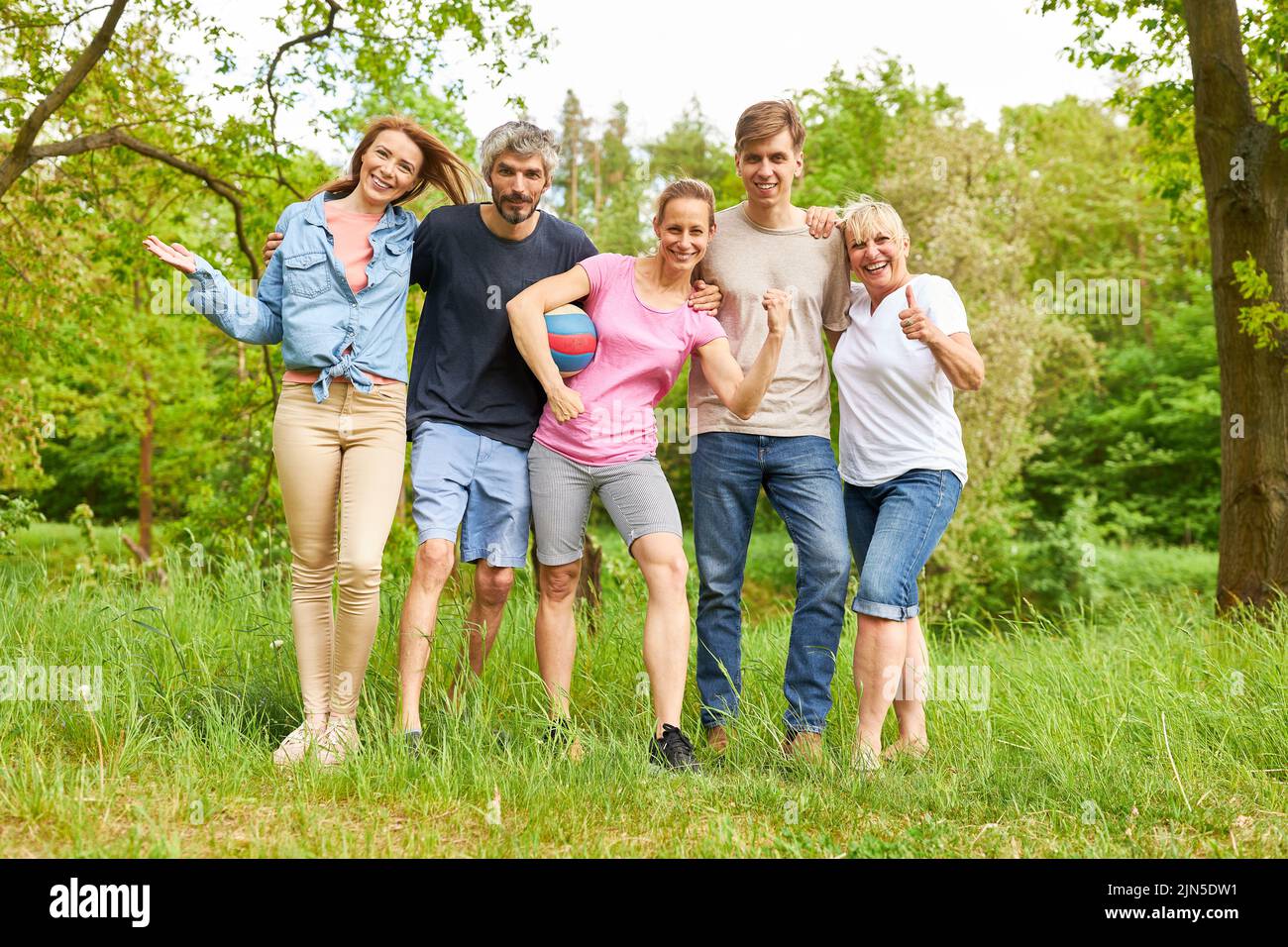 Five friends stand side by side as a soccer team on a meadow in nature in summer Stock Photo
