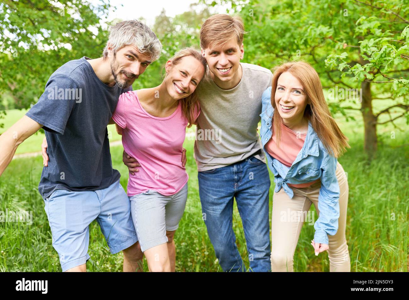 Happy young people as friends or siblings hugging on a summer outing Stock Photo